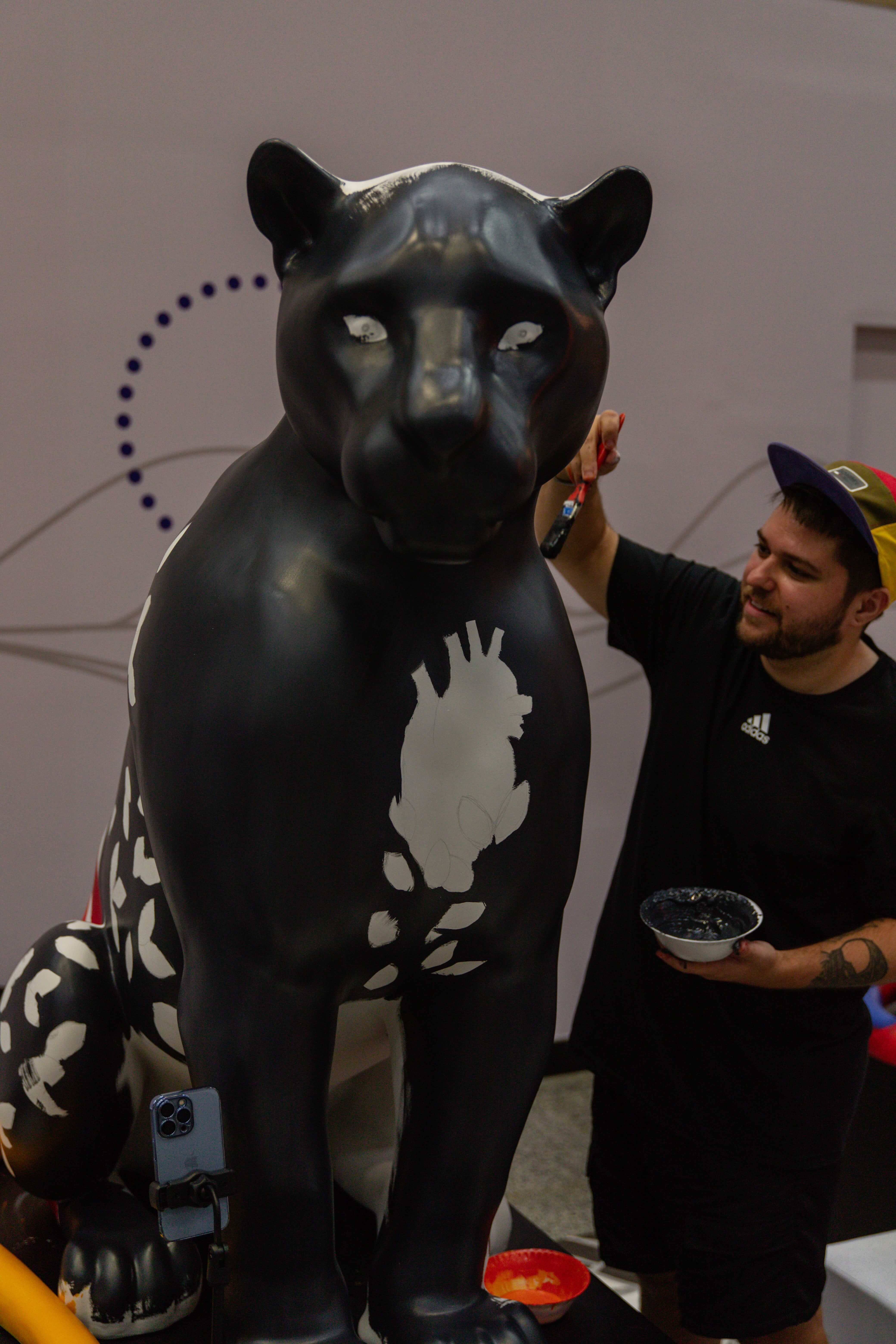 Artista pintando escultura de onça-pintada na Jaguar Parade